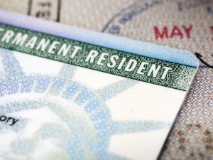 image-a-green-card-lying-on-an-open-passport-close-up-full-frame-187591458-5aa6c5caa9d4f900369f3d3d