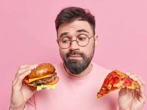 image-man-feels-hesitant-whether-eat-hamburger-pizza-prefers-eating-junk-food-wears-round-spectacles-jumper-pic_32ratio_900x600-900x600-28985